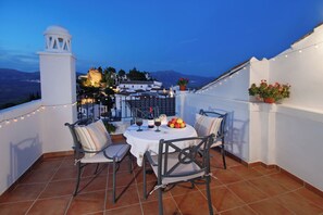 A terrace with a table set for two, chairs, a bottle of wine, and a bowl of fruit. - Casa Bonita, an authentic Andalusian village experience. Pets-hispeed WIFI-airco (Comares)