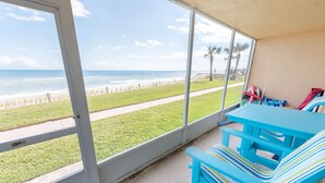 Eine überdachte Terrasse mit Blick auf den Strand, einem Tisch und Stühlen.
