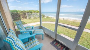 Eine überdachte Terrasse mit blauen, gestreiften Stühlen und Blick auf das Meer.