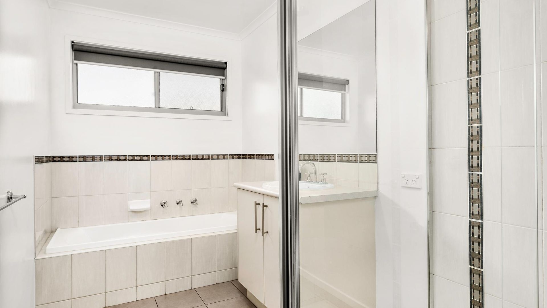 A modern bathroom with a bathtub, a shower area, and a vanity with a mirror.