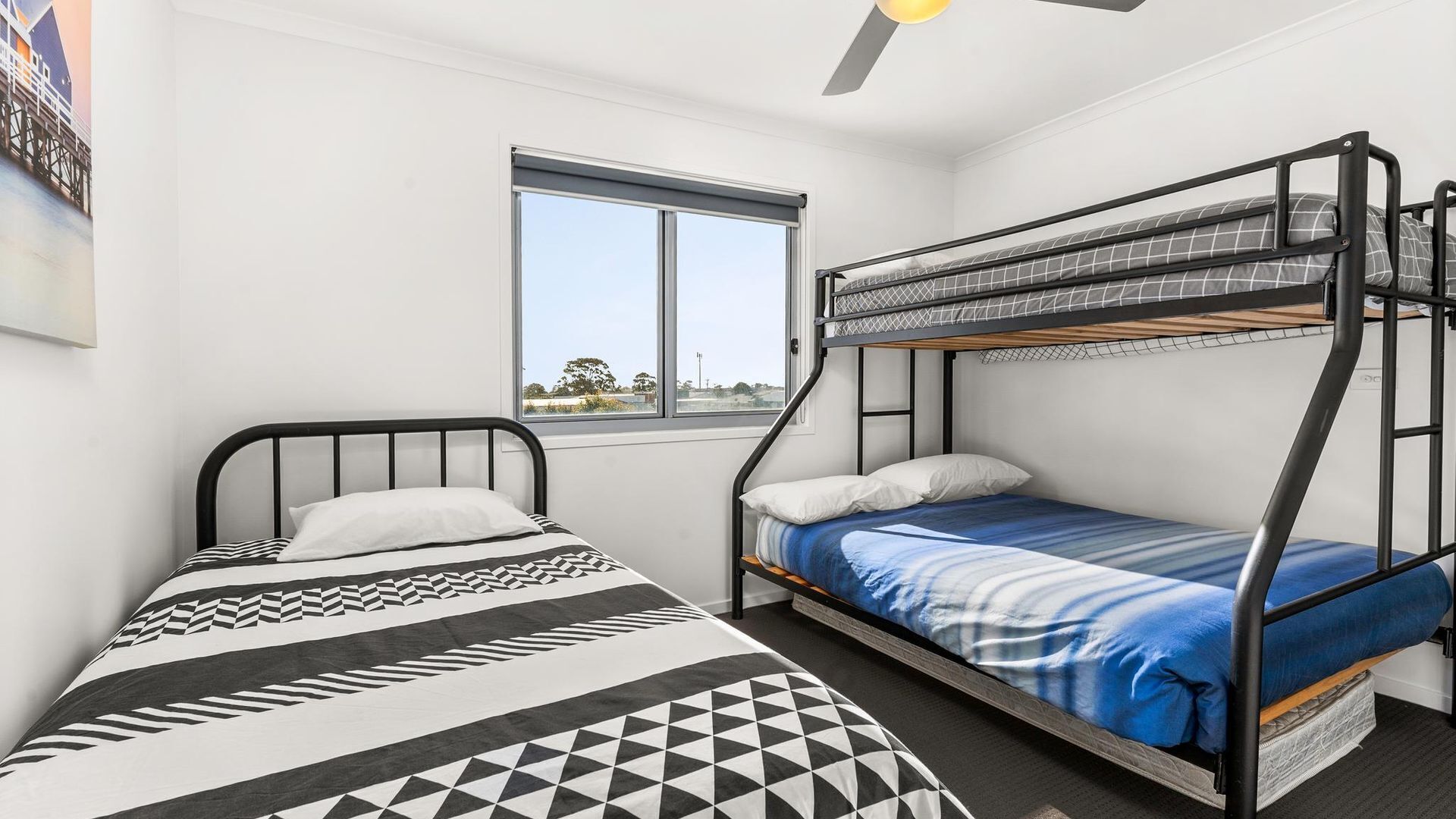 Un dormitorio con dos camas, una con cubrecama estampado geométricamente y la otra con cubrecama a rayas azules y blancas.