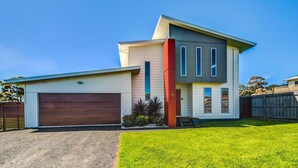 A modern two-story house with a garage, a well-maintained lawn, and a wooden fence. - Casa Killara - sleeps 14 (COWES)