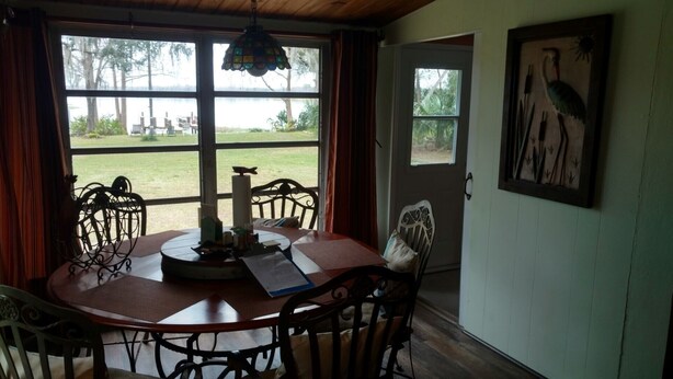 Uma sala de jantar com mesa e cadeiras de madeira, luminária de vitrais e vista para o exterior.
