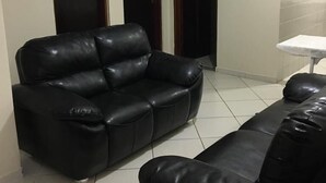 Ein Wohnzimmer mit einer schwarzen Ledersofa, einem kleinen Tisch und einer Wanduhr.