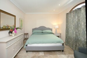 A bedroom with a bed, dresser, mirror, and curtains.