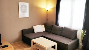 Un salon avec un canapé, une petite table, une lampe et un tableau encadré au mur.