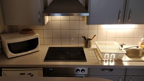 Une cuisine équipée d’un four à micro-ondes, d’une cuisinière, d’un lave-vaisselle et d’un évier avec un égouttoir.