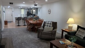 Ein modernes Wohnzimmer mit Essbereich, einer Couch, einem Couchtisch und einer Lampe.