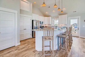 A spacious kitchen with white cabinetry, a central island with bar stools, and pendant lighting.