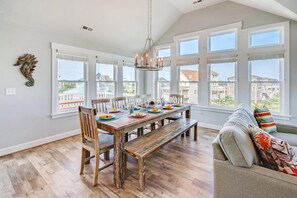 Comedor con una mesa de madera preparada para seis comensales, ventanas amplias y vistas a edificios.