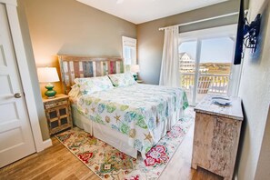 Un dormitorio con cama, mesitas de noche, cómoda y ventana con vistas, además de una puerta.