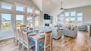 Un vaste espace de vie comprenant une table à manger dressée pour le repas, un grand canapé et un téléviseur fixé au mur.