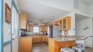 Una cocina con armarios de madera, encimera de granito y refrigerador de acero inoxidable.