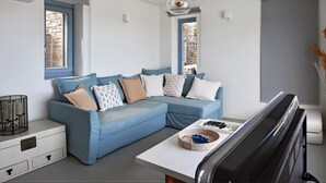 A modern living room with a blue sectional sofa, a flat-screen TV, and a small table with decorative items.