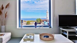 A modern living room with a large window offering a scenic view, a flat-screen TV, and a minimalist decor.
