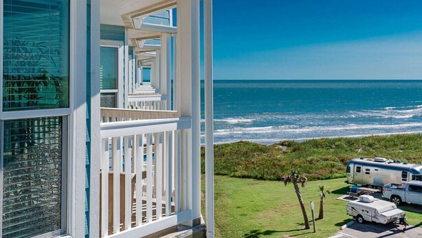 A coastal house with a balcony overlooking the ocean, a white RV parked in the driveway, and a clear blue sky. - Great Views! Heated Pools, Hot Tubs & Easy Beach Access (Galveston)