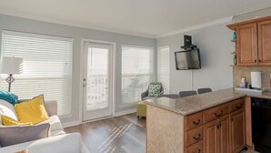 A modern kitchen with wooden cabinets, a built-in oven, and a flat-screen TV. - Great Views! Heated Pools, Hot Tubs & Easy Beach Access (Galveston)