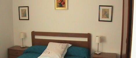 Un dormitorio con una cama individual, dos mesitas de noche y dos cuadros en la pared.