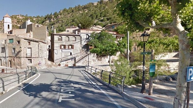 A narrow street with a pedestrian bridge, buildings with historical architecture, and a parking sign. - Rural apartment Racó de les Heures for 8 people (Arbolí)