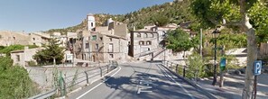 A narrow street with a pedestrian bridge, buildings with historical architecture, and a parking sign. - Rural apartment Racó de les Heures for 8 people (Arbolí)