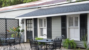 A patio with a table and chairs, a door, and windows with shutters. - Prime Location just steps from the French Quarter & 3 Blocks to Bourbon St, (New Orleans)