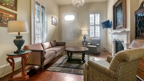 A living room with a brown leather sofa, a round coffee table, patterned armchairs, a chandelier, and a fireplace. - Prime Location just steps from the French Quarter & 3 Blocks to Bourbon St, (New Orleans)