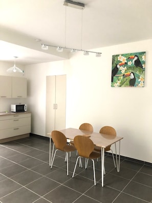 A modern kitchen with white cabinets, a microwave, and a dining area with a table and chairs.