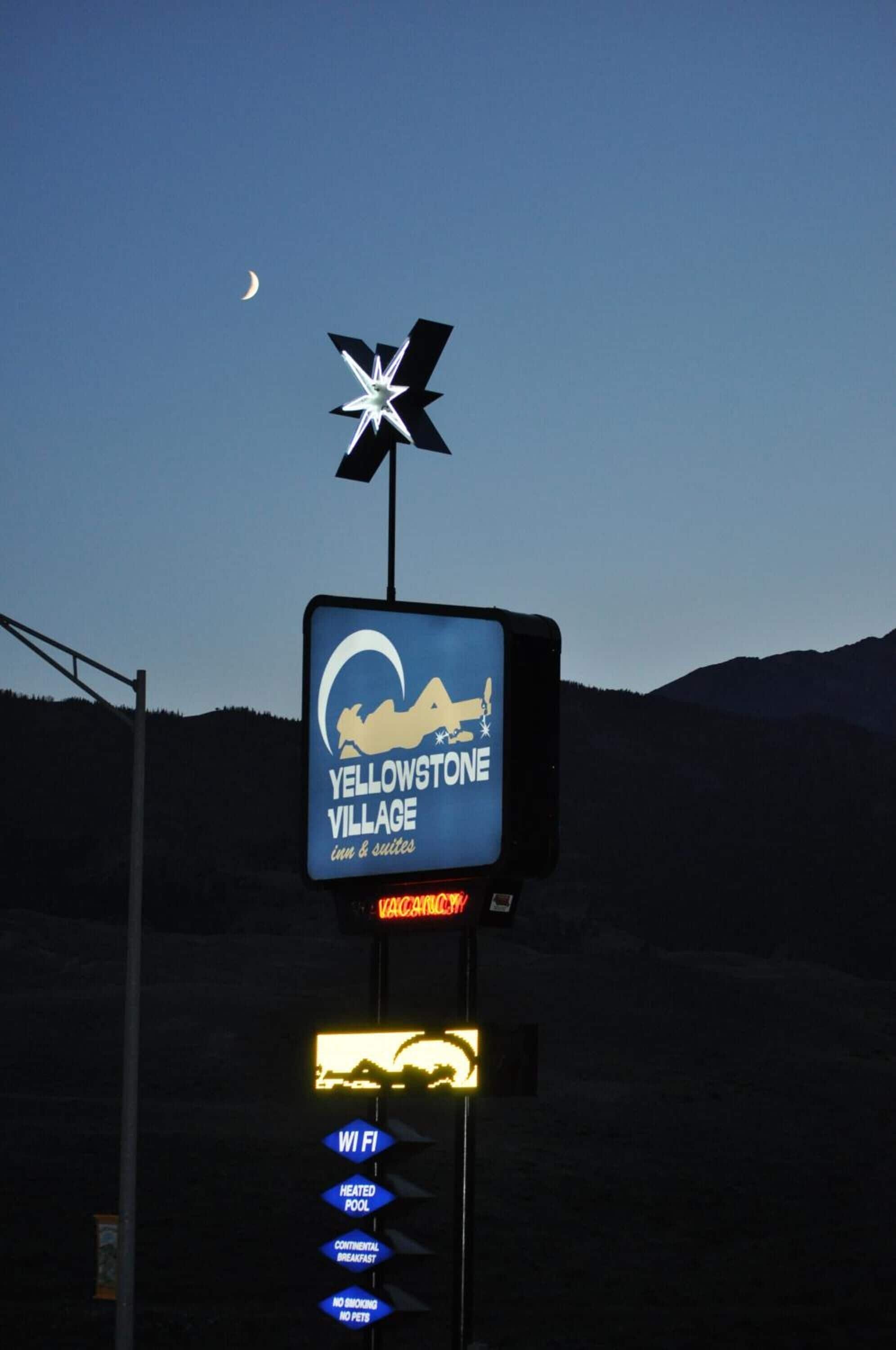 A sign for Yellowstone Village with amenities like WiFi, heated pool, continental breakfast, and no smoking.