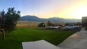 A parking area with a picnic table, a grassy field, and mountains in the background. - Yellowstone Village Inn and Suites (Gardiner)