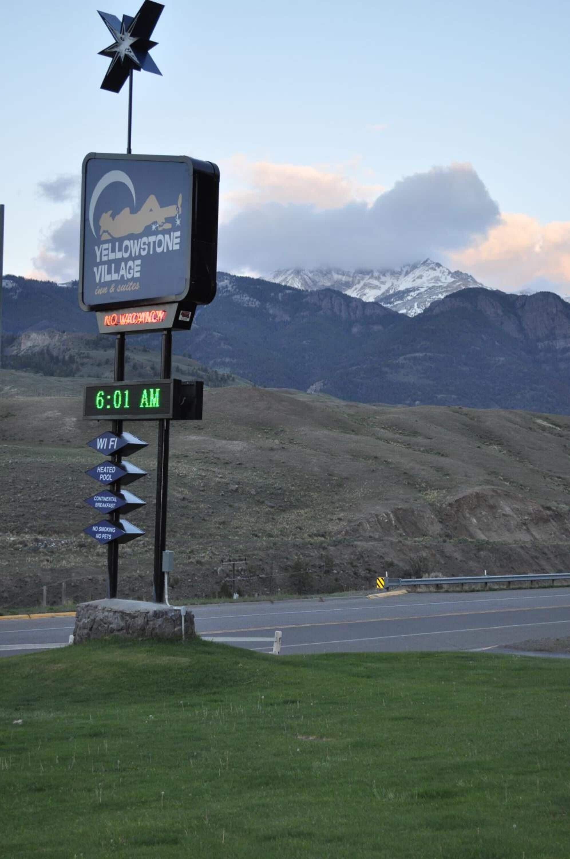 A sign for Yellowstone Village with amenities like WiFi, heated pool, continental breakfast, and no smoking.