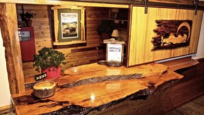 A wooden reception desk with a rustic design, featuring a welcome sign, a framed poster, and a potted plant. - Yellowstone Village Inn and Suites (Gardiner)