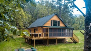 A wooden cabin with a covered deck and a staircase leading to the main floor.