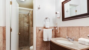 Un baño con ducha, inodoro, lavabo y espejo.