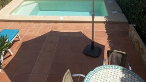 Ein Poolbereich mit Meerblick, umgeben von Grünflächen und einer gefliesten Terrasse.