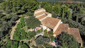 A villa with a terracotta roof, surrounded by dense greenery and hills in the background. - Mazet de La Tour - private terrace and shared swimming pool -Vallée des Baux (Paradou)