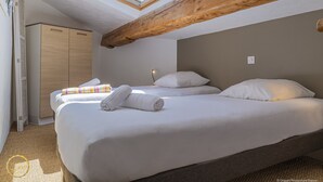 A bedroom with a skylight, wooden beams, a wardrobe, and a bed with pillows and a striped blanket. - Mazet de La Tour - private terrace and shared swimming pool -Vallée des Baux (Paradou)