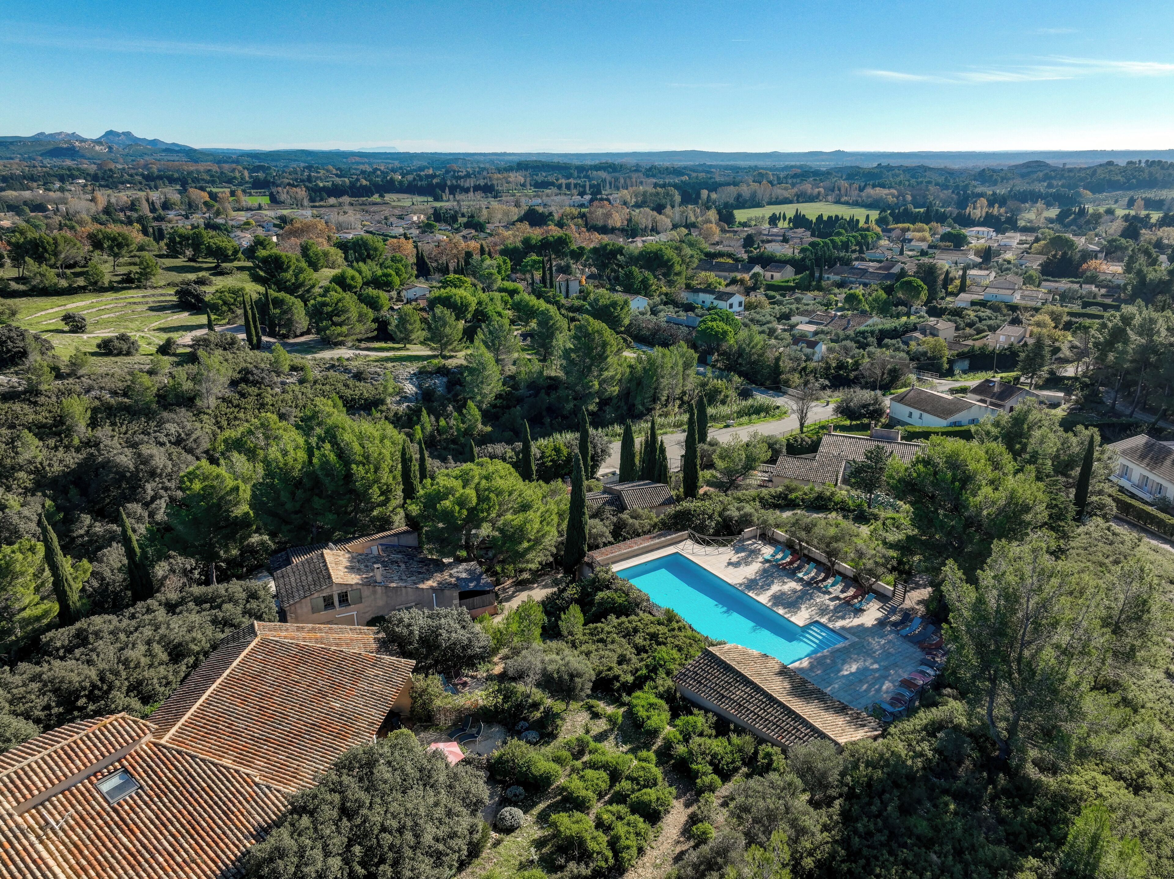 Vista aérea de um bairro residencial com uma grande piscina cercada por vegetação exuberante e casas.