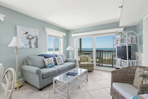 A living room with a sofa, armchair, coffee table, and a television on a stand. - 3 bedroom spacious oceanfront condo. Outdoor pool. (North Myrtle Beach)
