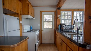 A compact kitchen with wooden cabinets, a white refrigerator, a stove, and a sink.