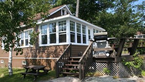 A house with a large front porch, a wooden deck, and a picnic table.