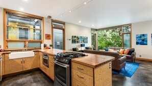 Une cuisine moderne dotée d’un îlot central, d’appareils électroménagers intégrés et de grandes fenêtres.