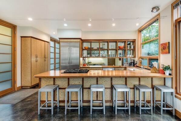A modern kitchen with a central island, bar stools, stainless steel appliances, and a large window. - Luxury Modern on Newport- Westside | Walk | Dog friendly (Bend)