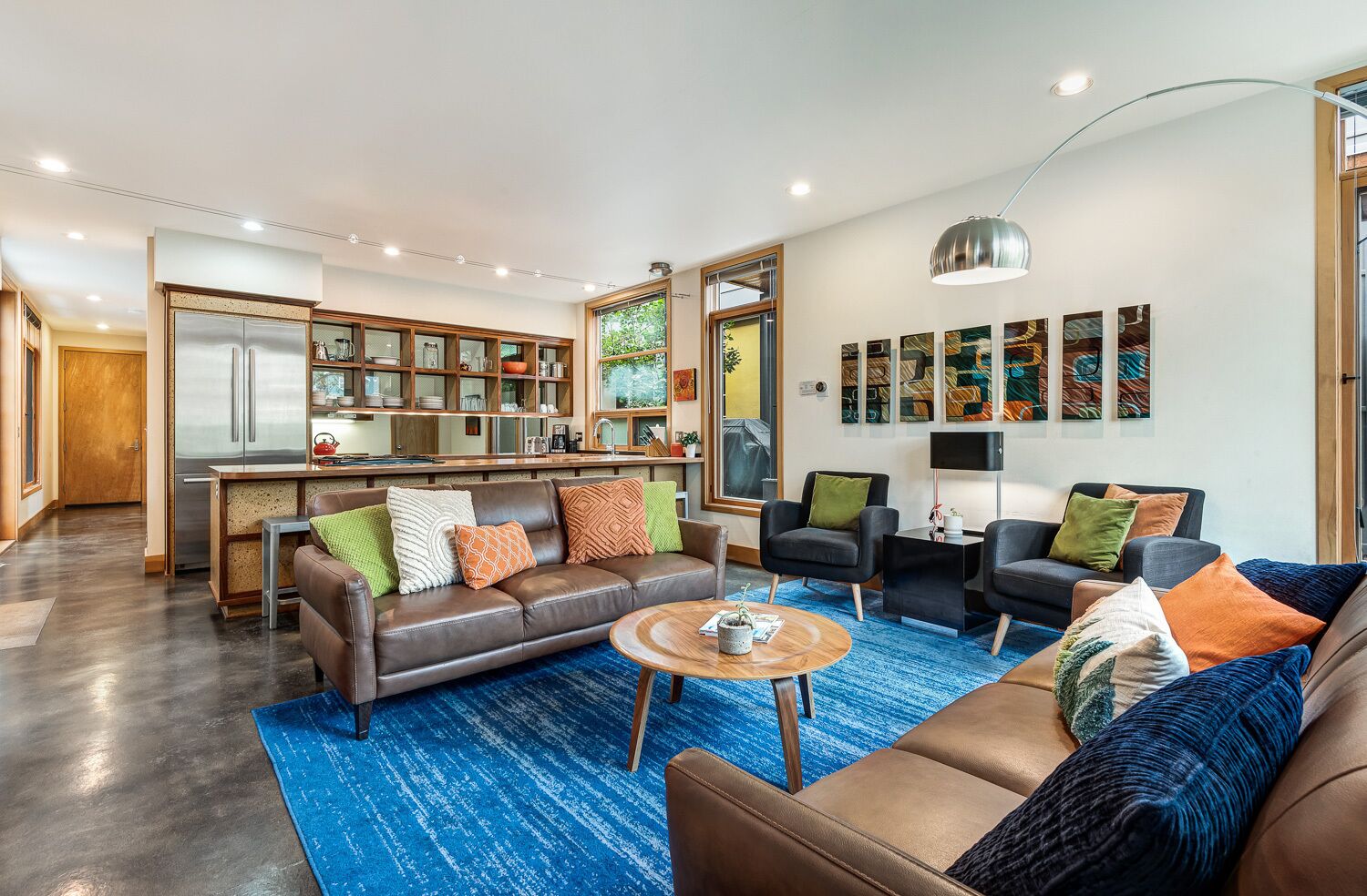 A modern living room with a brown leather sofa, a coffee table, and a blue carpet.