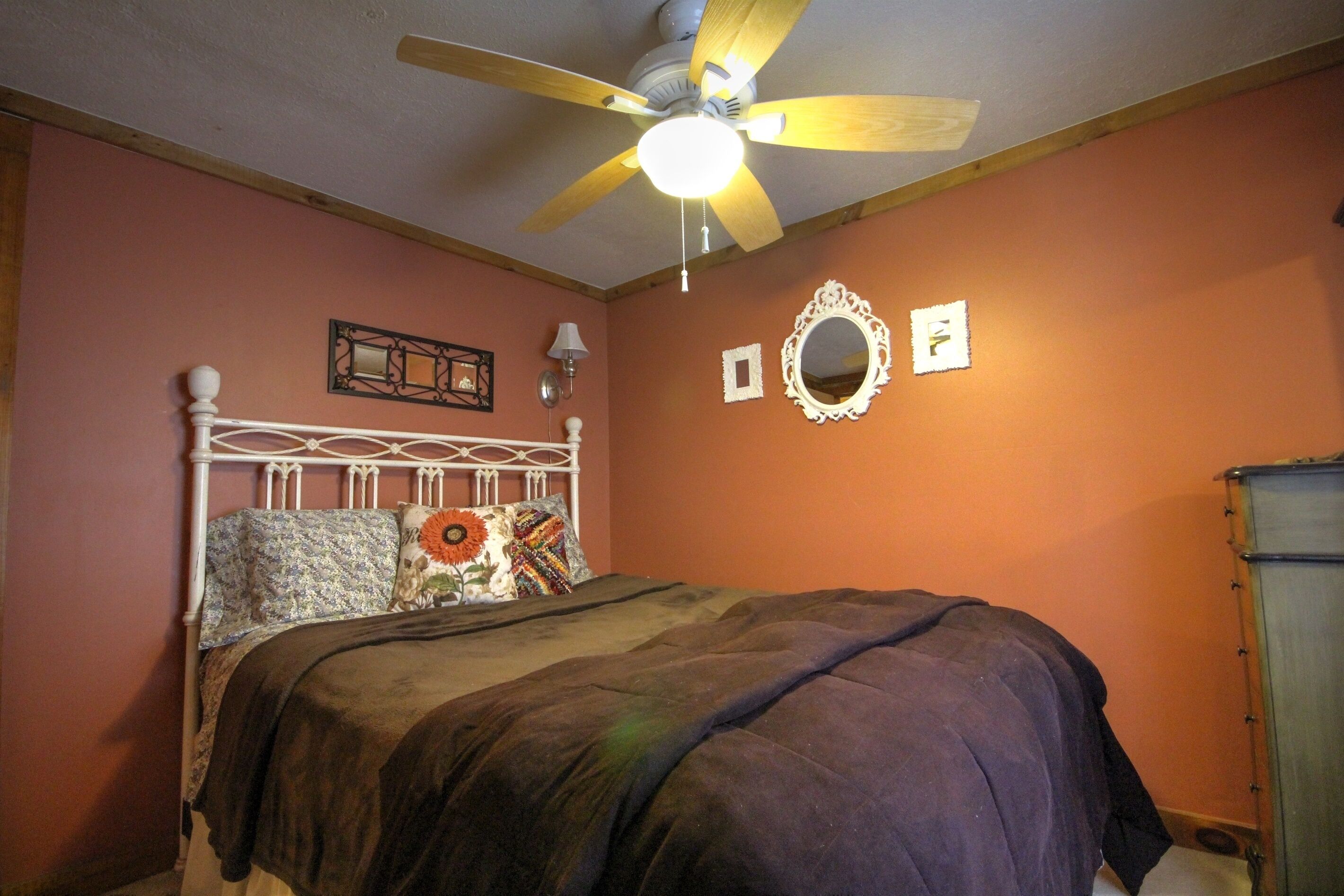 A bedroom with a bed, a ceiling fan, and a dresser.