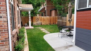 Un jardin avec une terrasse, une clôture en bois et un mur en briques.