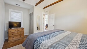 Une chambre à coucher avec un lit, une commode en bois et un téléviseur.