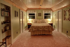 Een slaapkamer met een bed, twee nachtkastjes, een boekenplank en een spiegel.