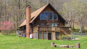 Eine Blockhütte mit Holzterrasse, großen Fenstern und Schornstein.