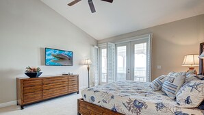 A bedroom with a bed, a dresser, a television, and a view of the outdoors. - Dolphin Watch | Beachfront on private Beach (Cape Haze)