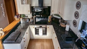 A modern kitchen with white cabinets, a central island, a built-in oven, and a stainless steel sink. - Boutique, 3 bedroom lodge in the heart of Northumberland with private hot tub (Newcastle upon Tyne)